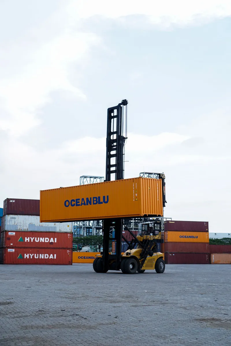 Chariot élévateur portuaire déplaçant un conteneur dans un terminal